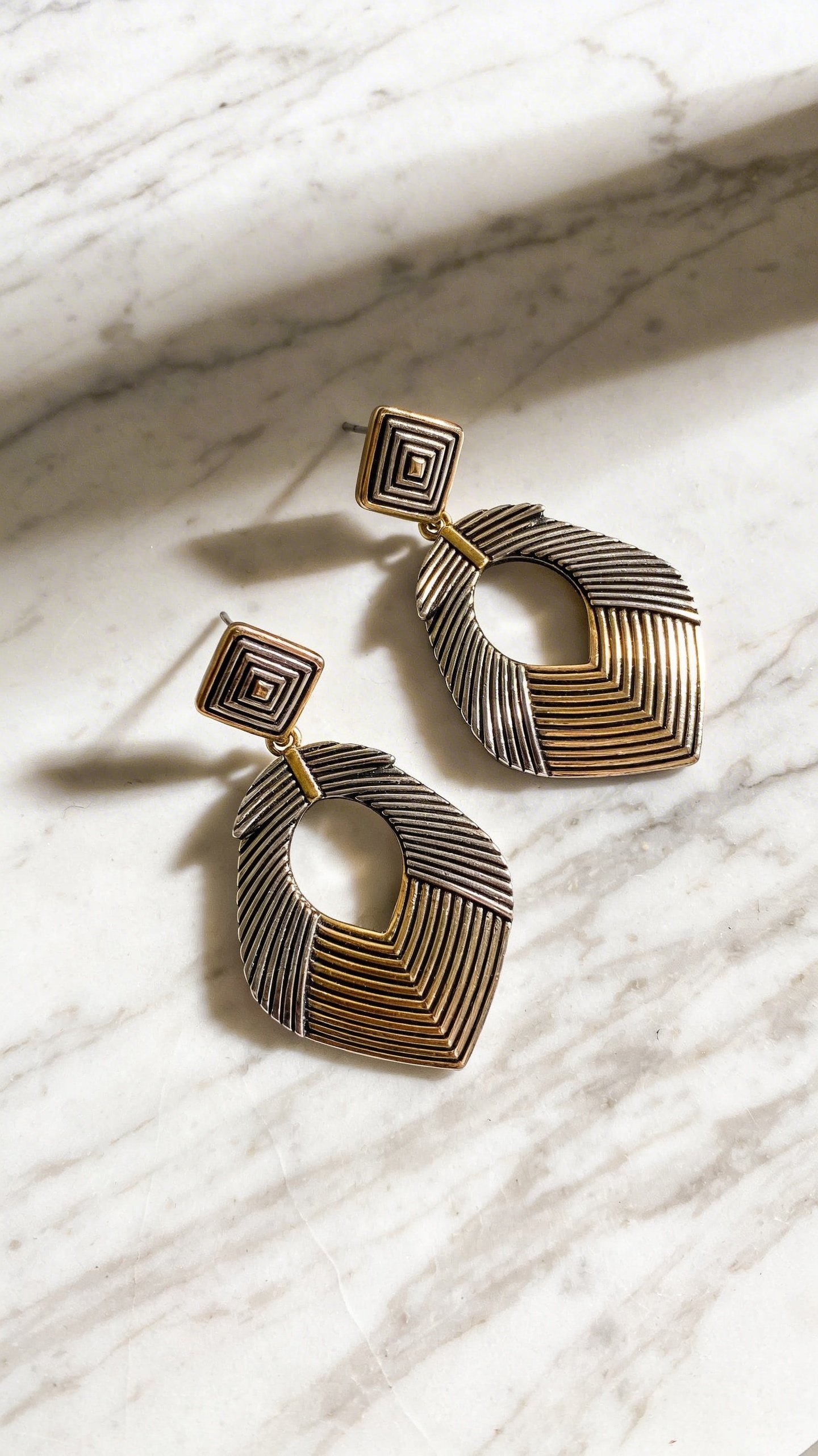 Oversized statement earrings on marble surface, professional lighting