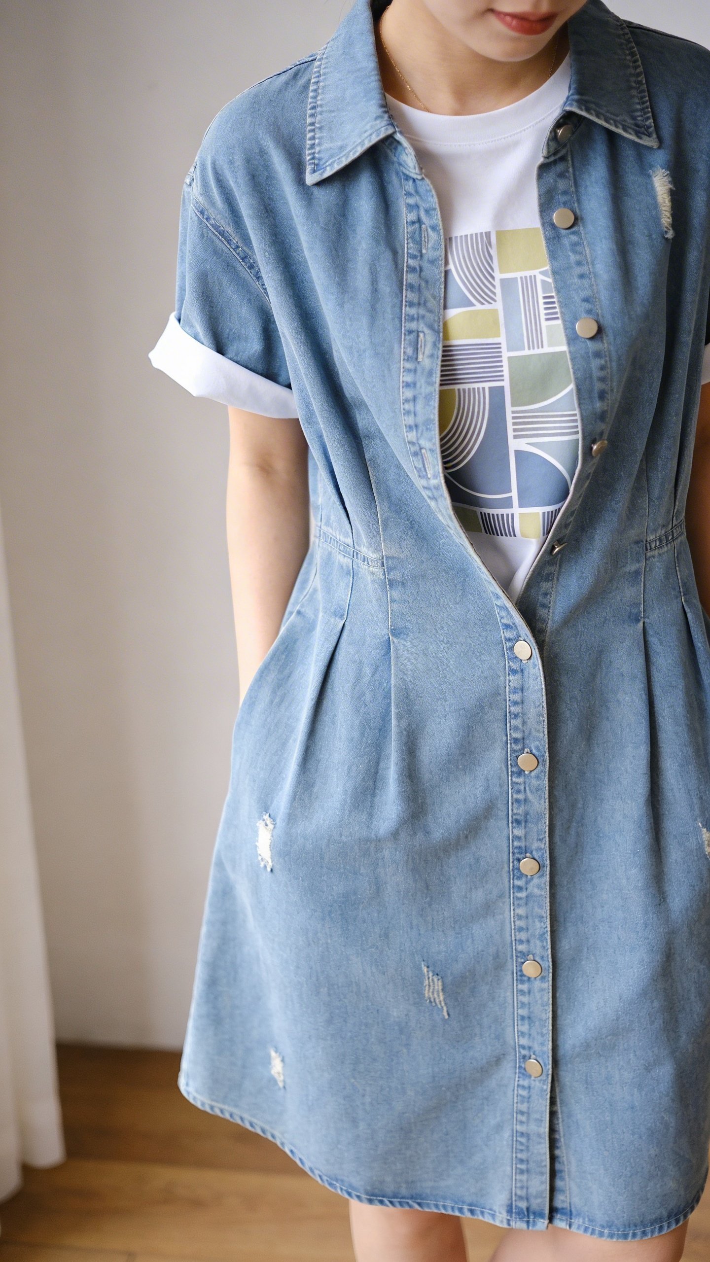Graphic tee layered under button-down denim dress