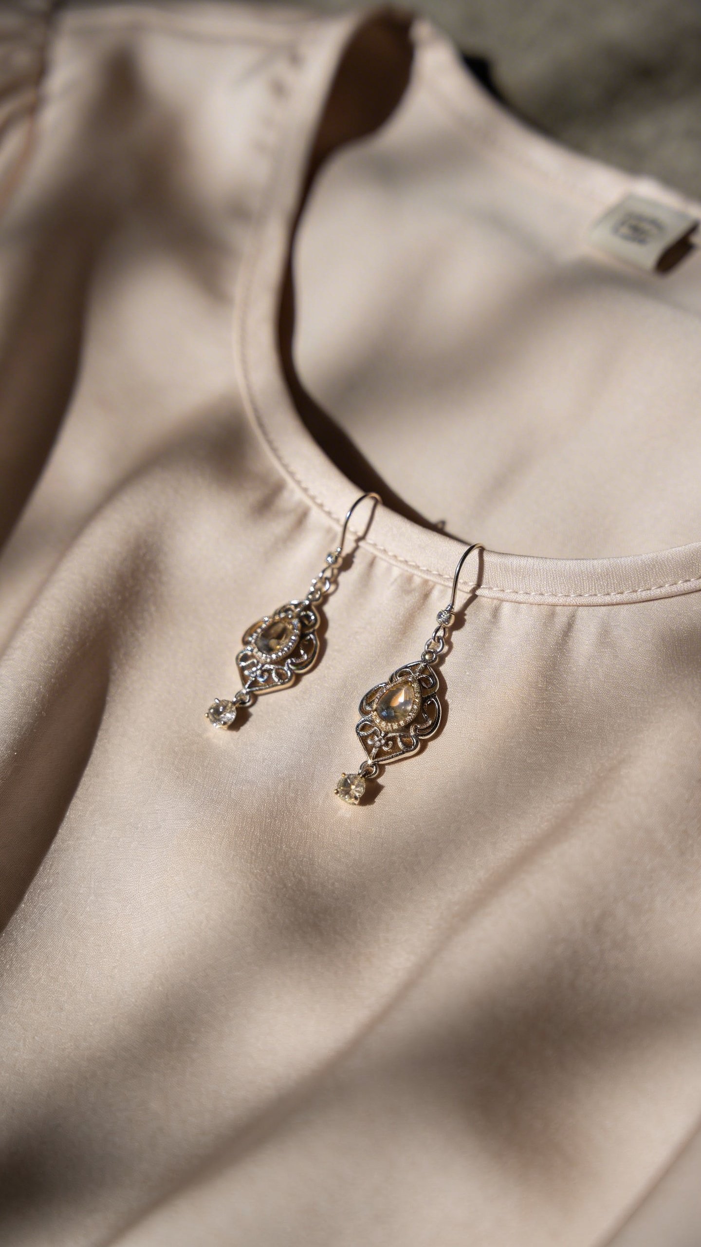 Elegant drop earrings showcased against scoop neck blouse