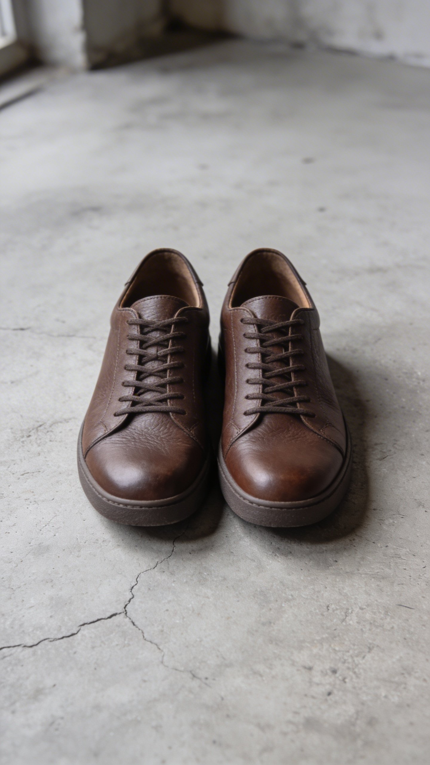Brown leather minimalist sneakers on concrete floor