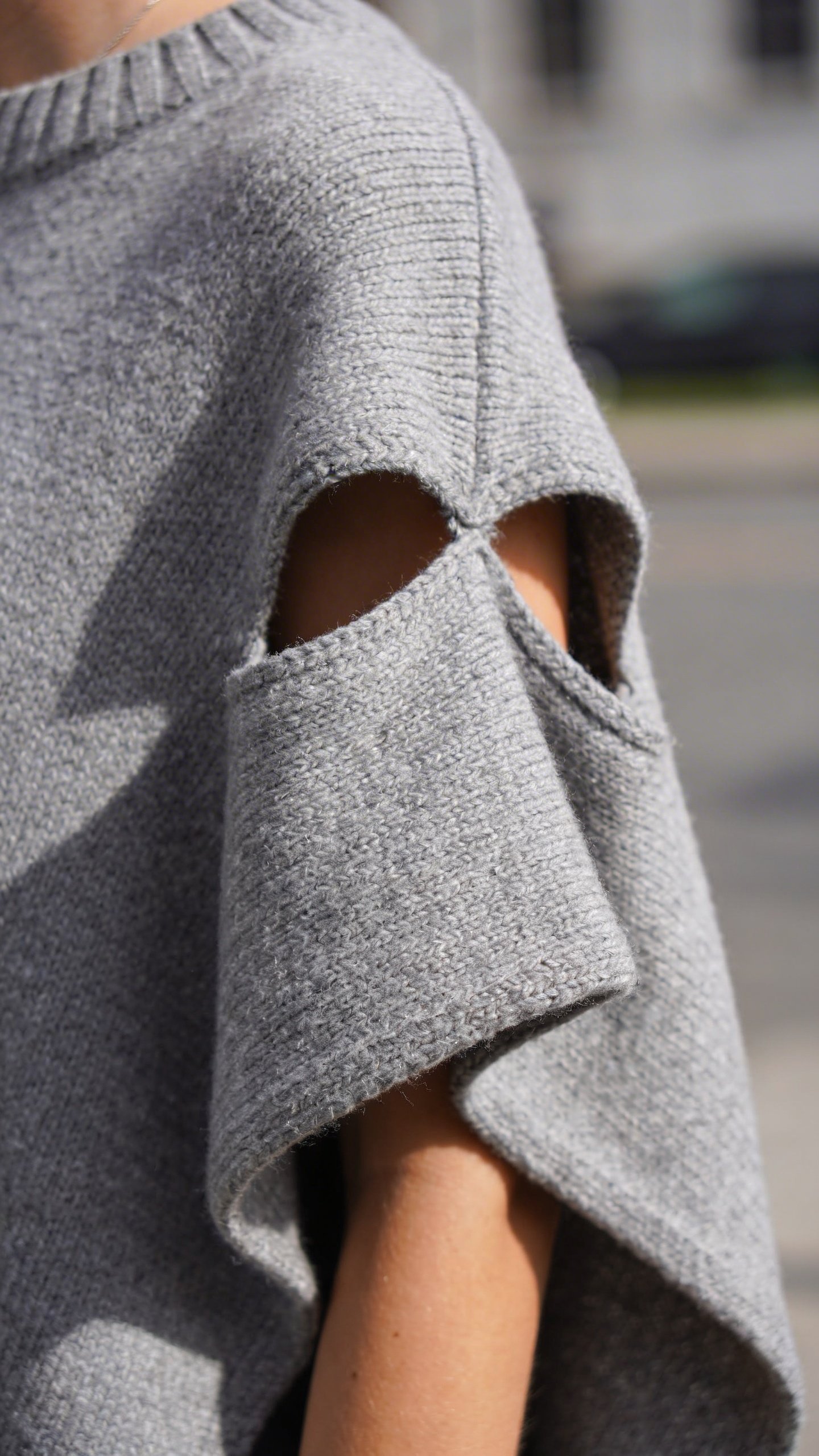 Closeup gray knit poncho with defined arm openings