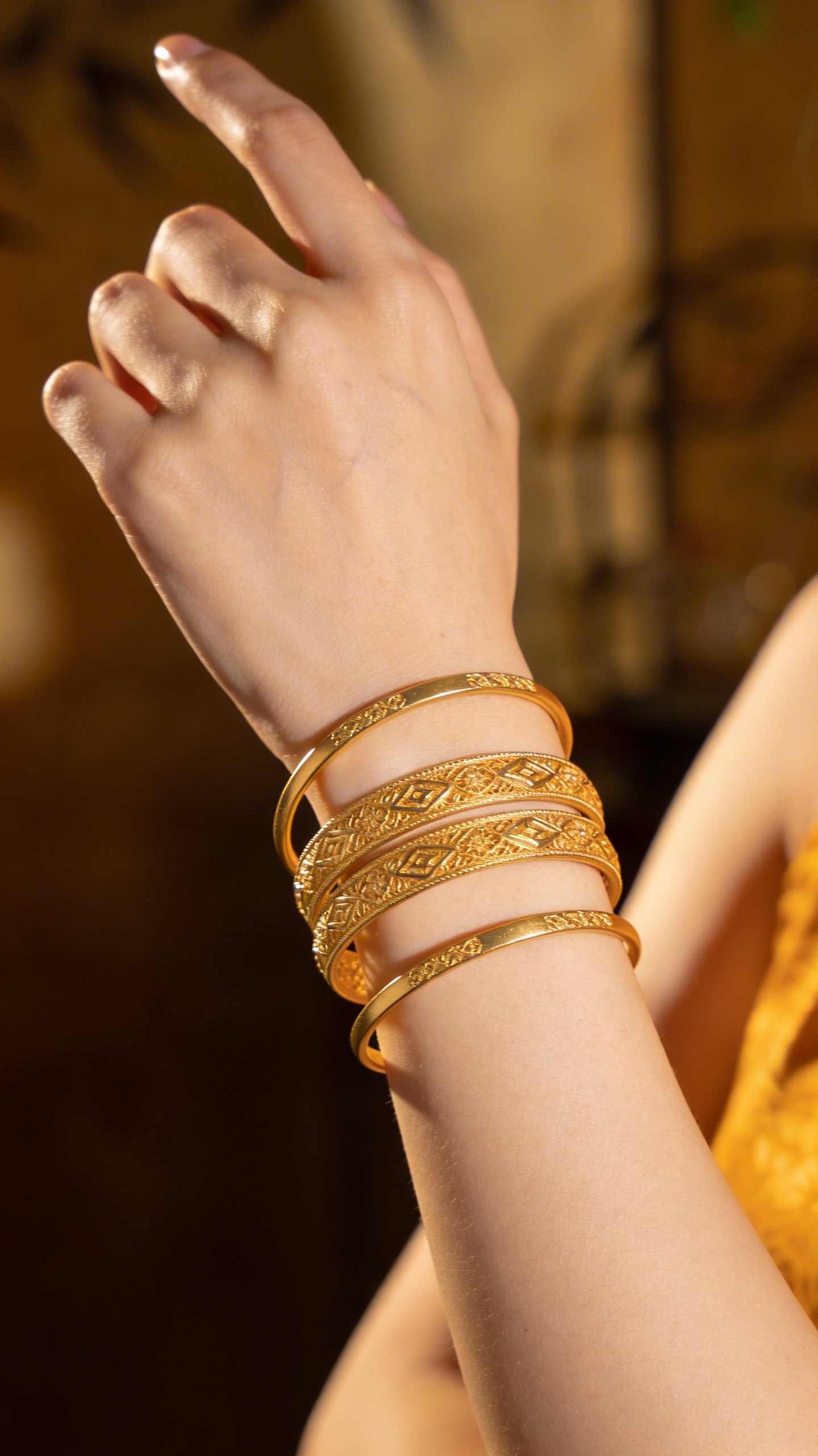 Woman's hand wearing stacked gold bangles, professional lighting