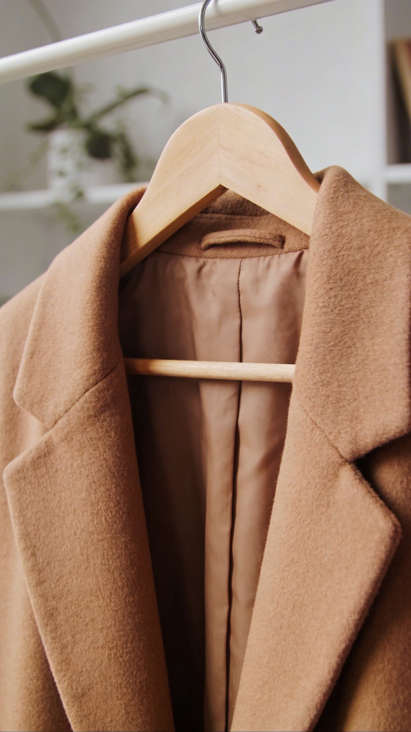 Camel wool overcoat hanging on minimalist wooden hanger