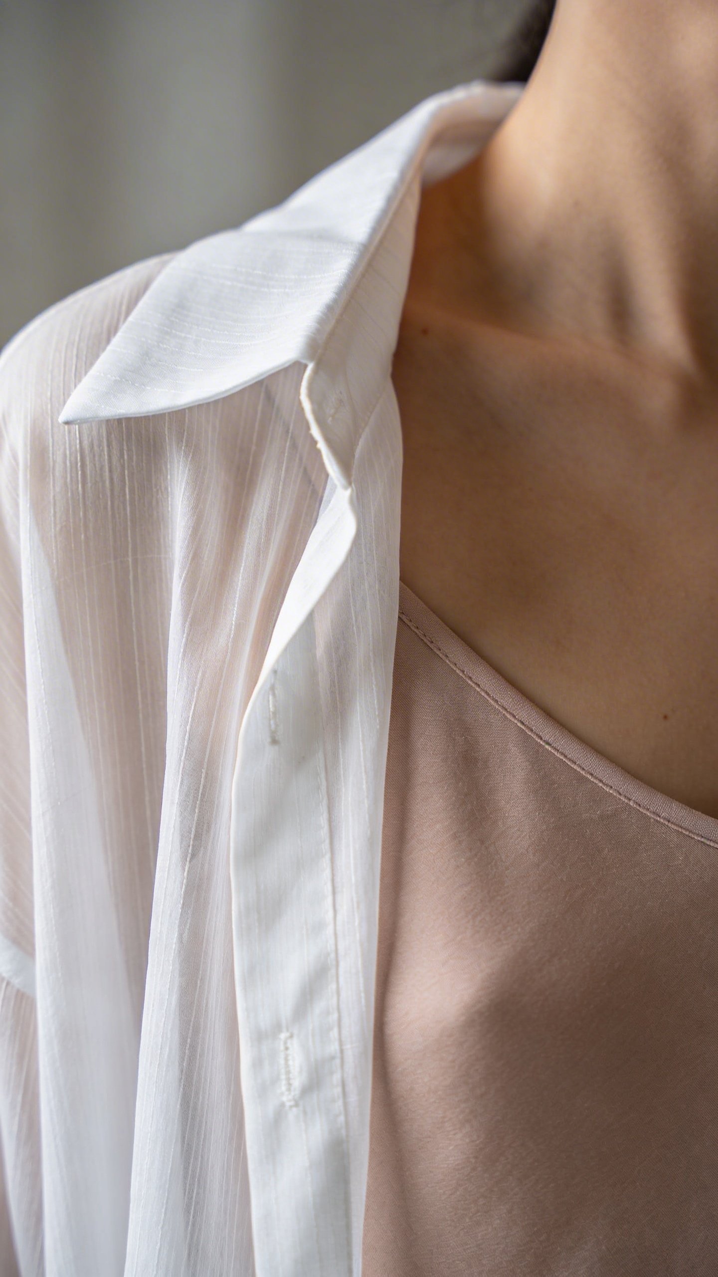 Closeup of white sheer blouse over nude camisole