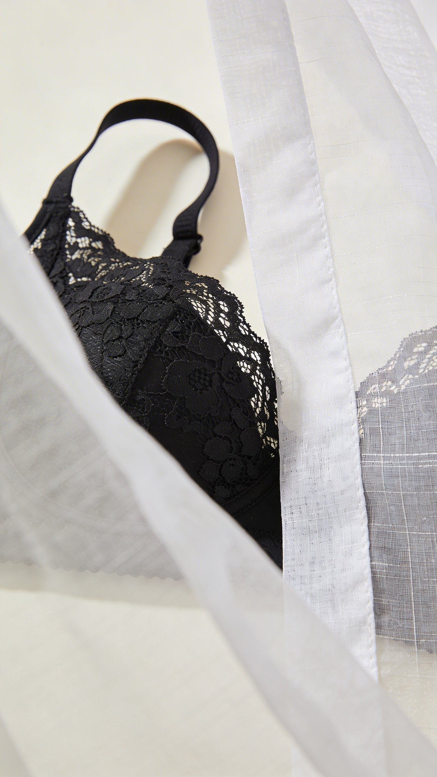 Black lace bralette under transparent white fabric closeup