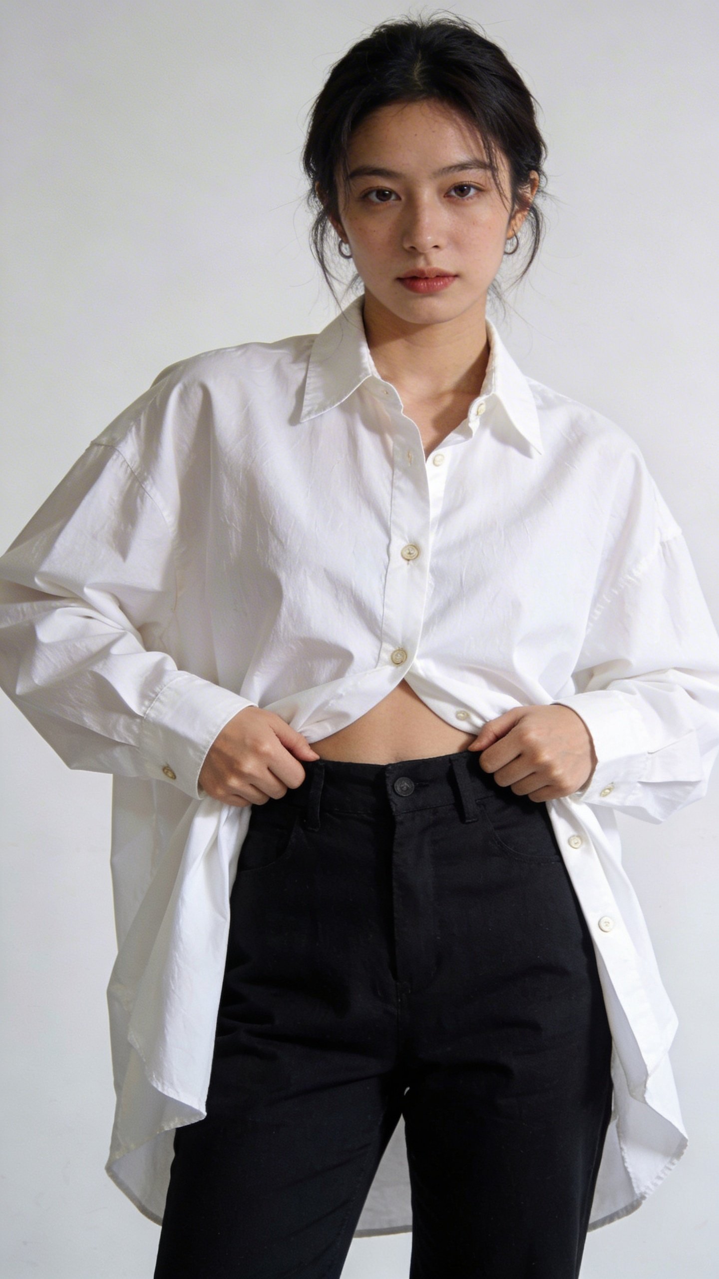 Woman demonstrating French tuck with oversized white button-down shirt