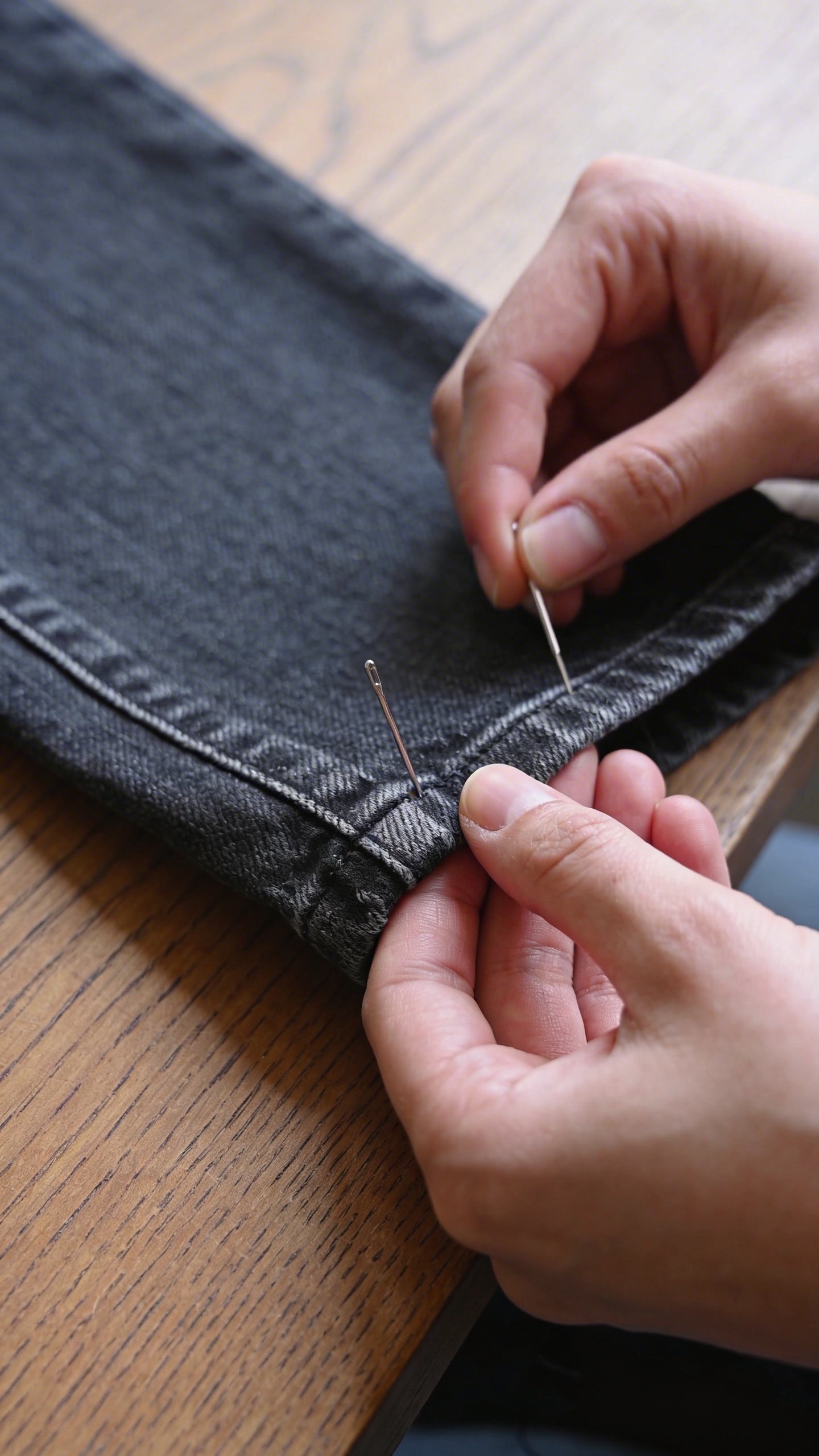 Hem of dark denim jeans being pinned for alteration