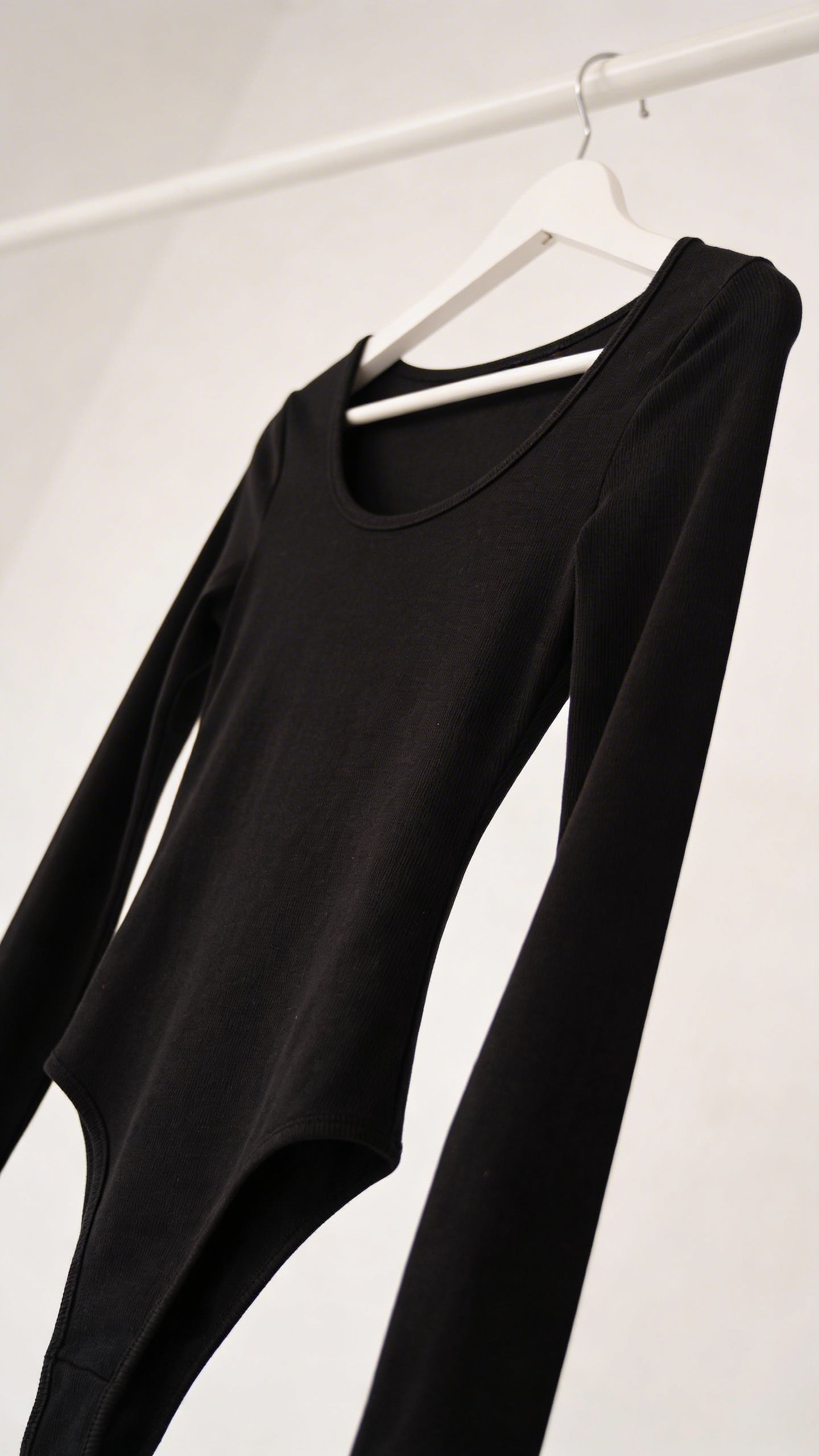 Black long-sleeved bodysuit on white hanger closeup