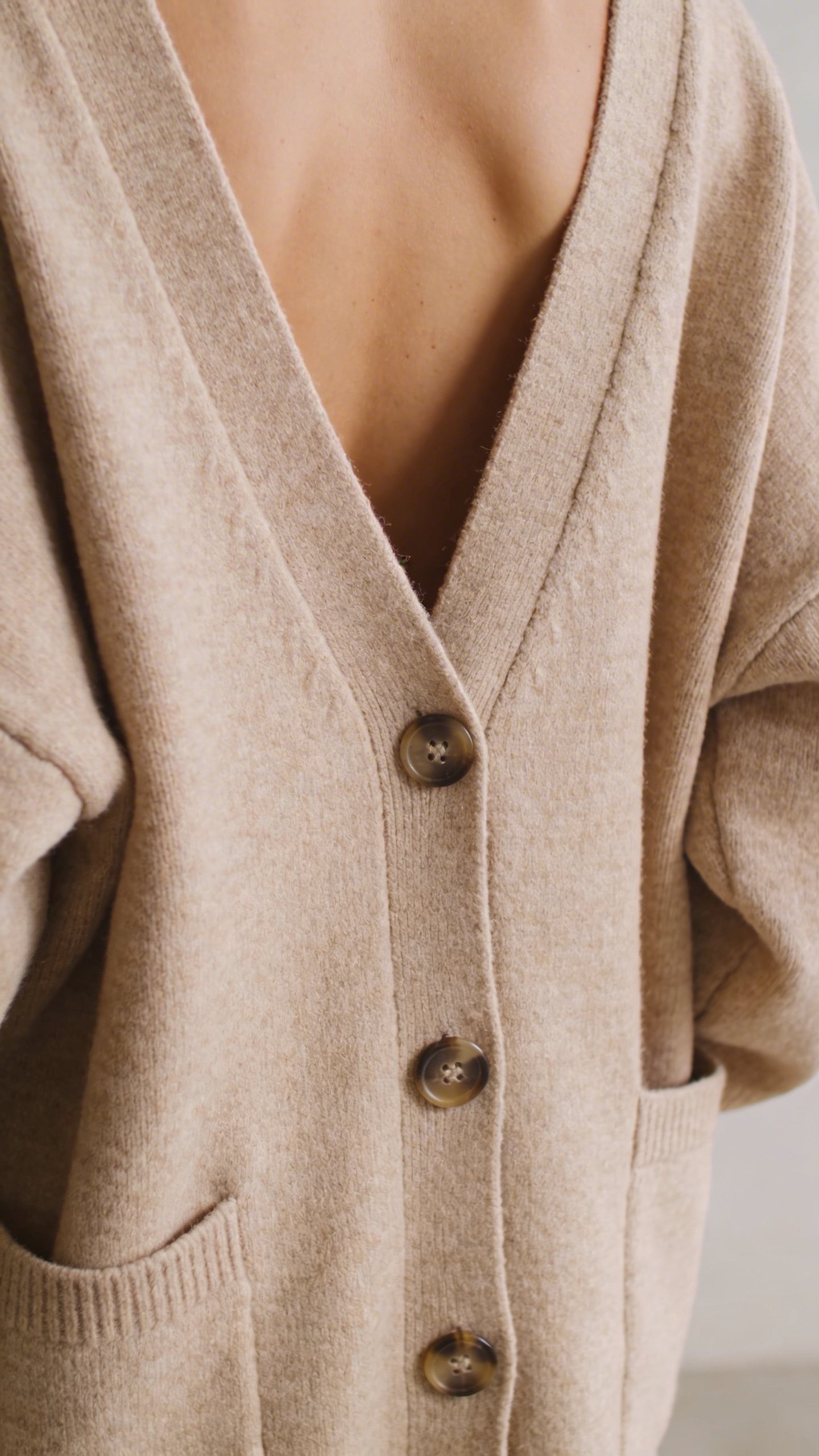 Oversized beige cardigan worn backwards showing button detail