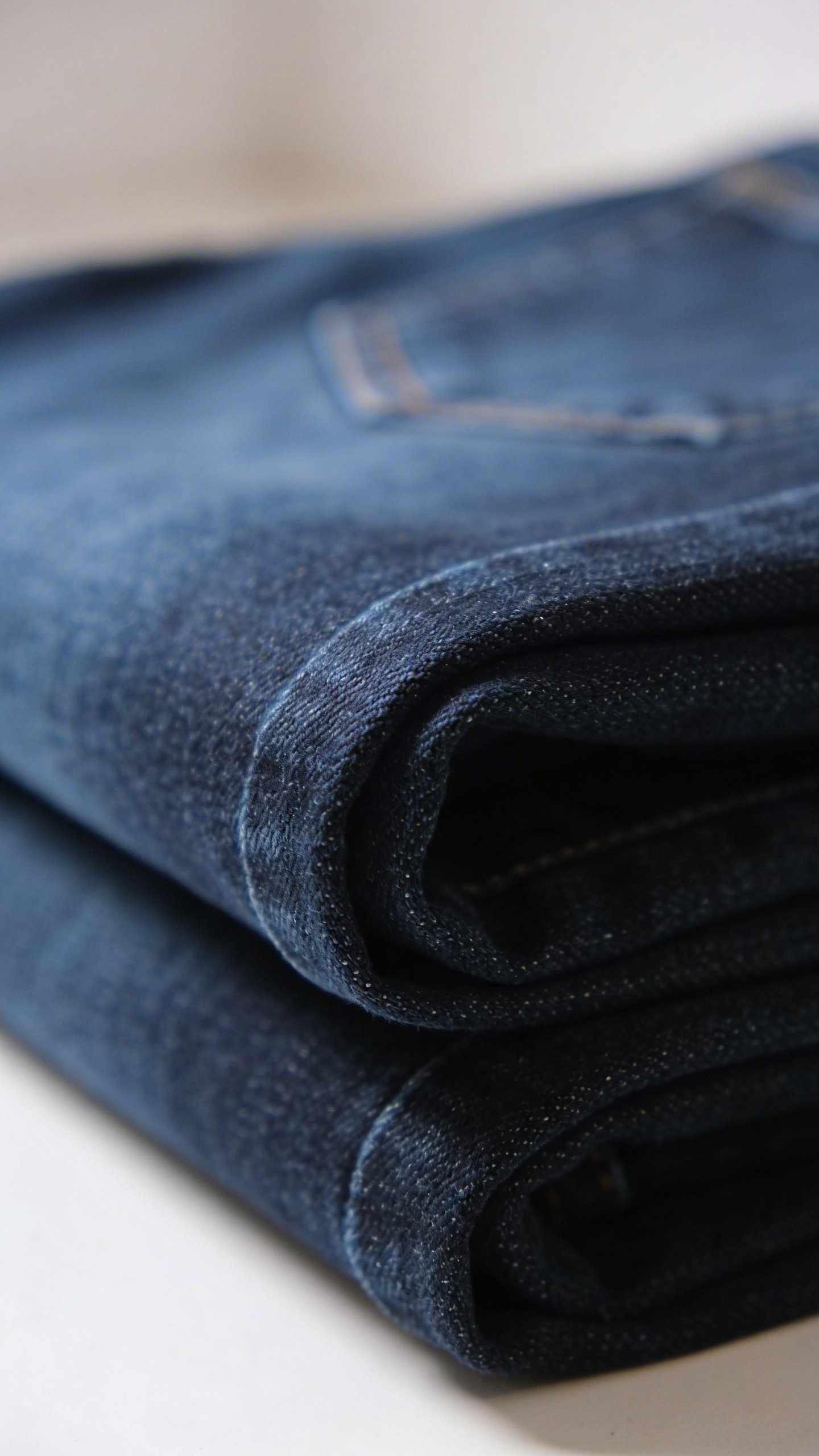 Closeup of folded dark wash fitted denim jeans