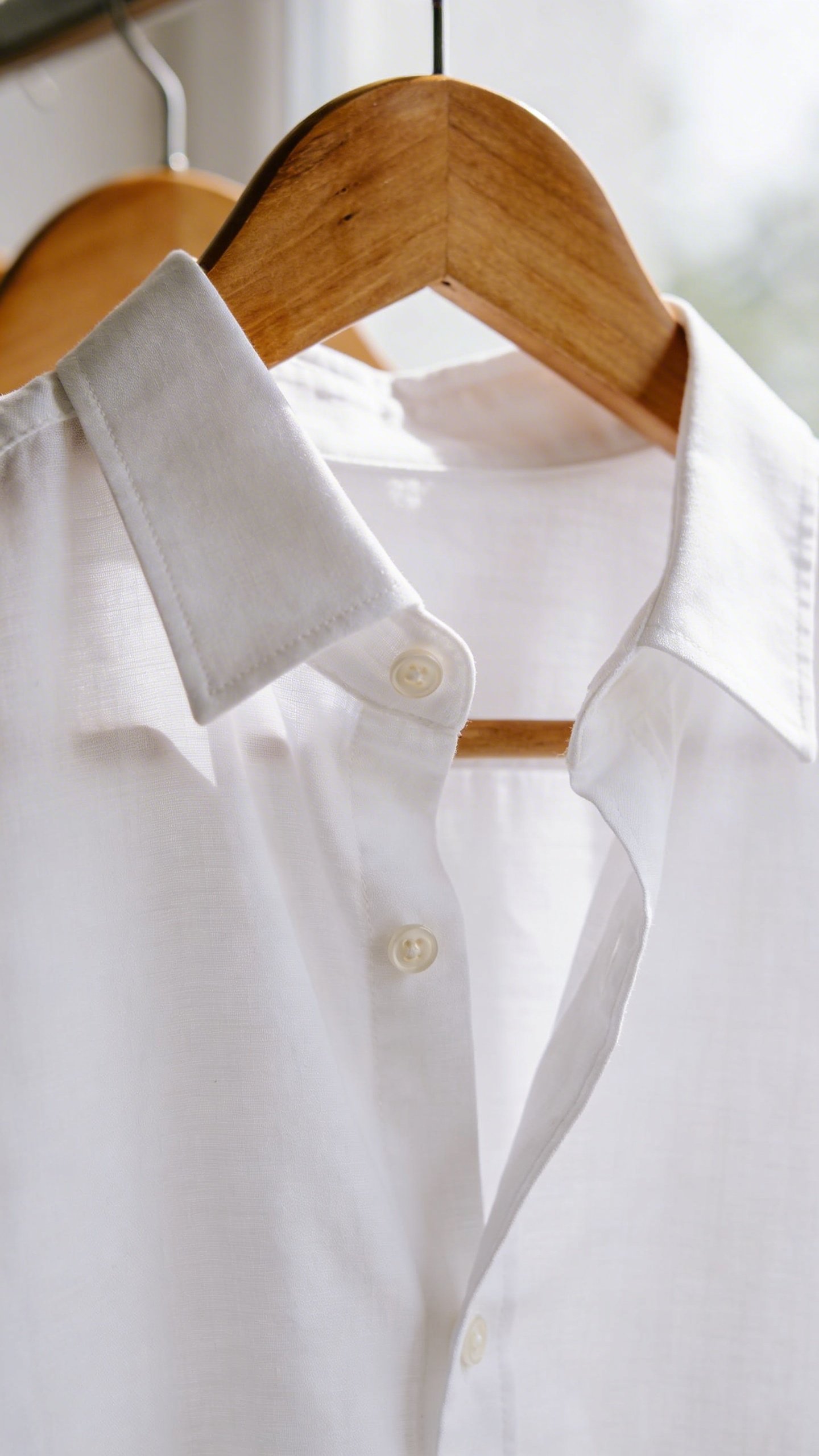 Crisp white button-down shirt on wooden hanger