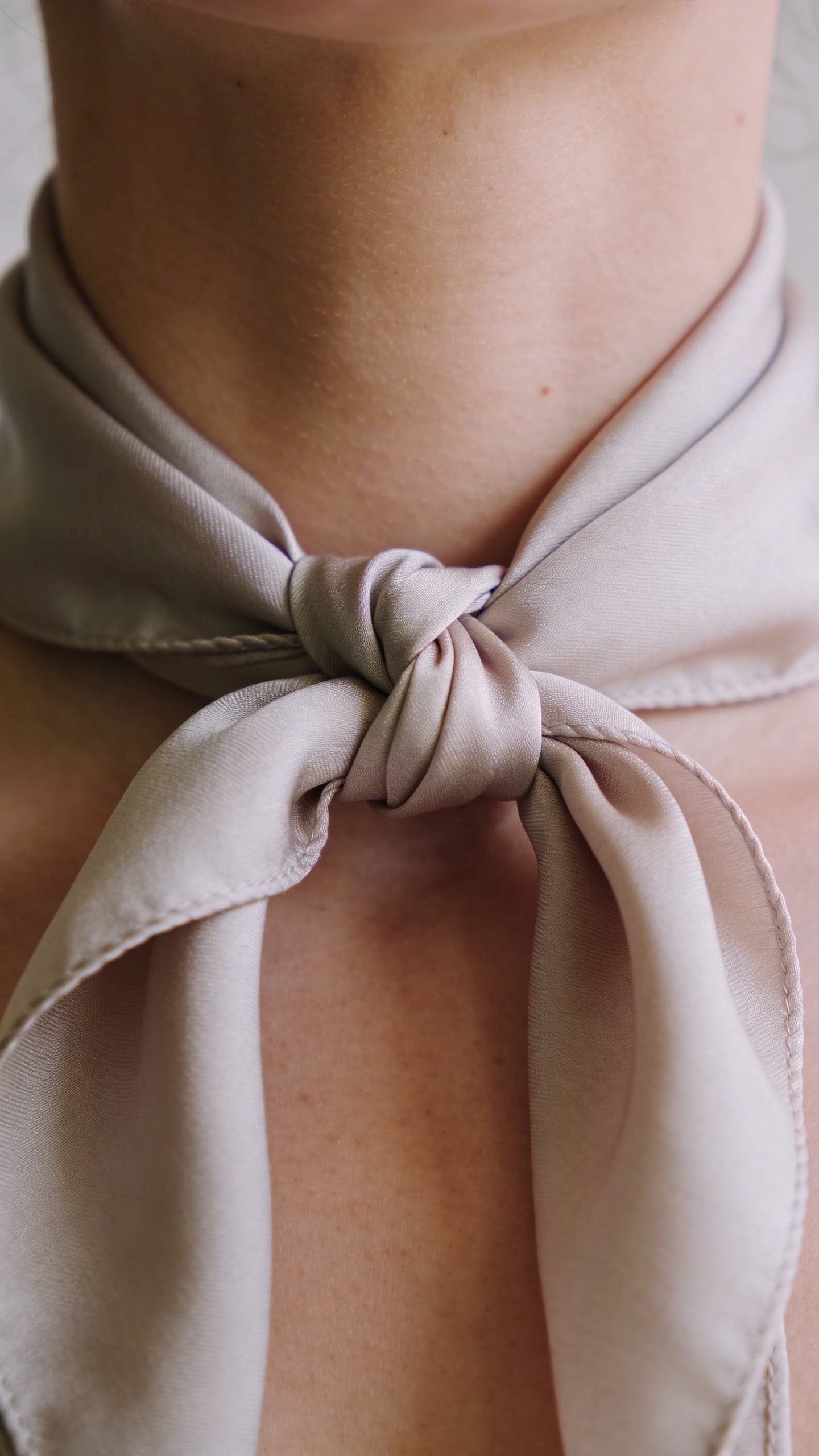 Silk scarf tied in French knot around neck closeup