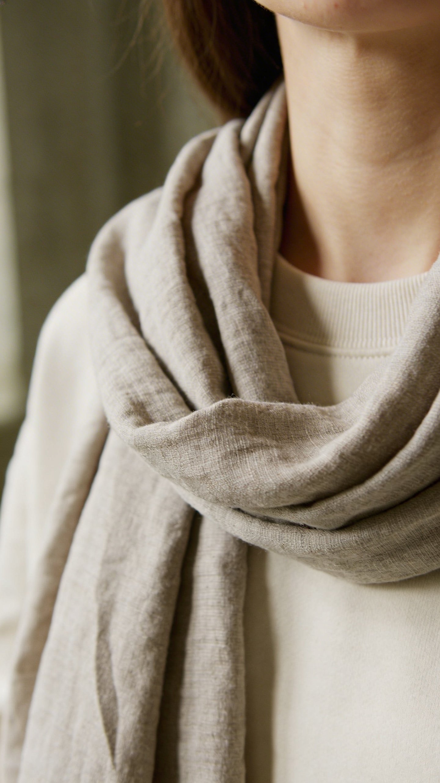 Folded scarf hanging loosely around woman's neckline detail