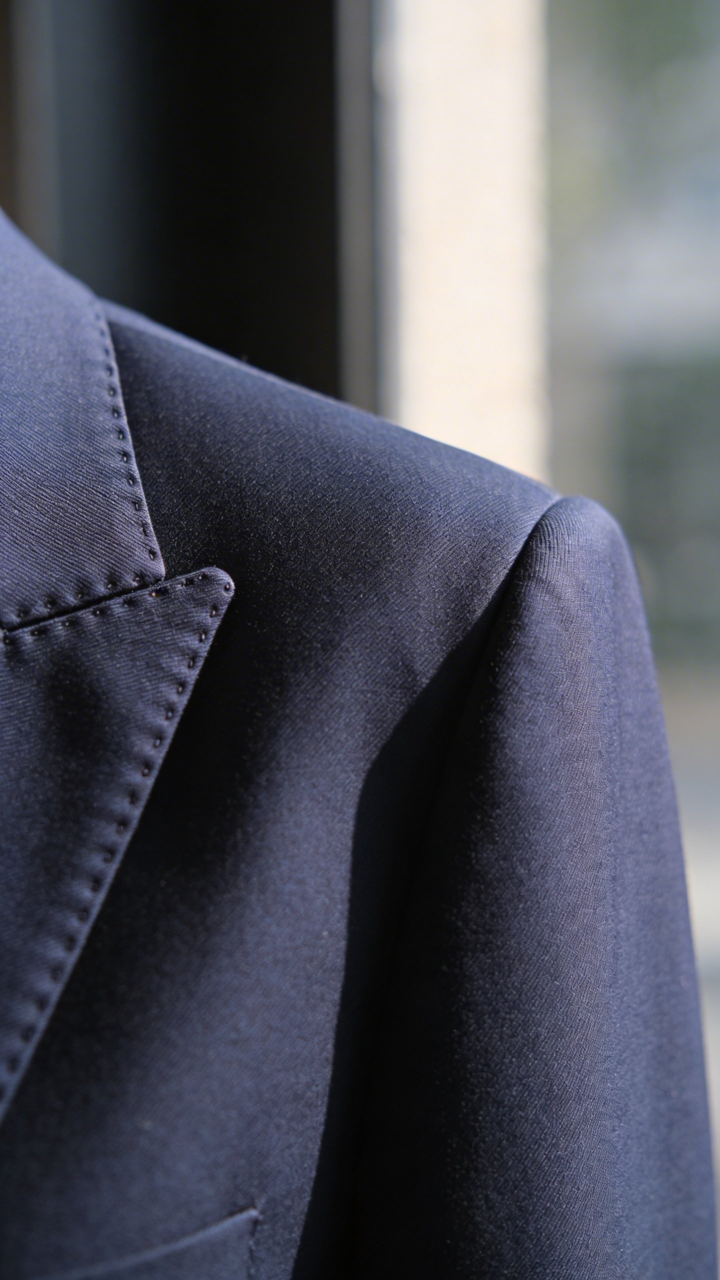 Closeup of tailored navy blazer shoulder seam detail