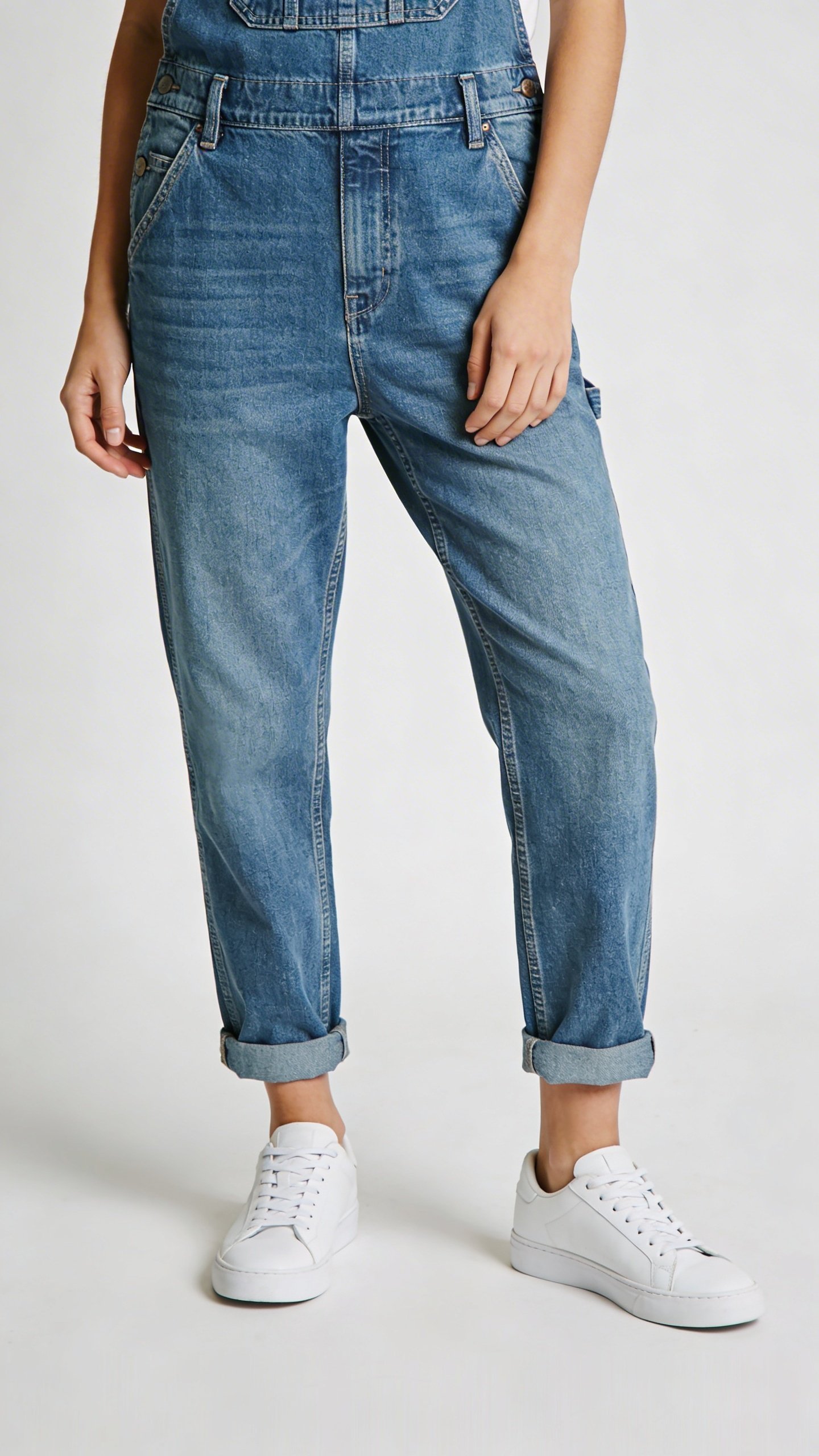 Casual denim jumpsuit with white sneakers, standing pose