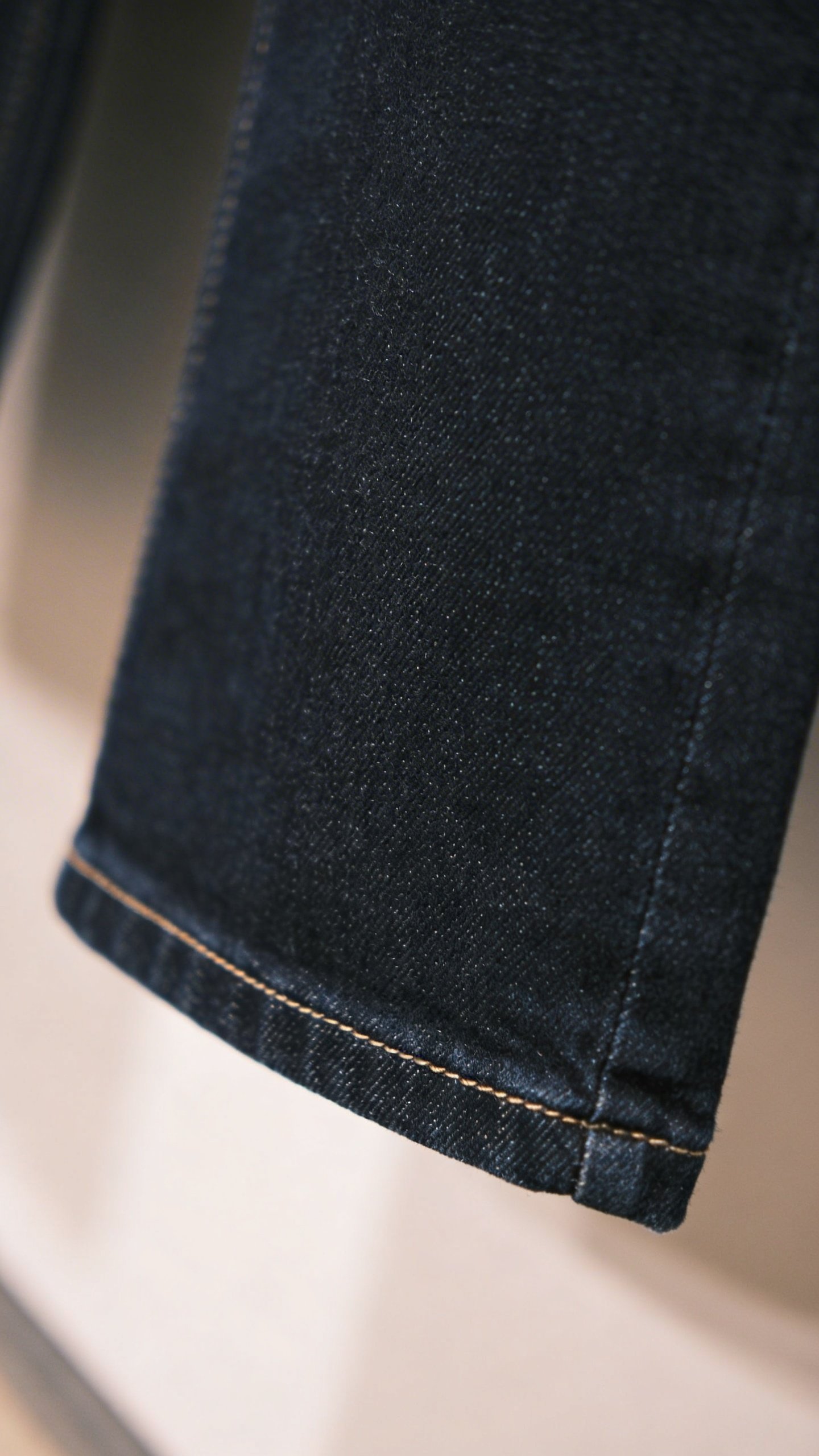 Closeup of perfectly hemmed dark denim jeans length