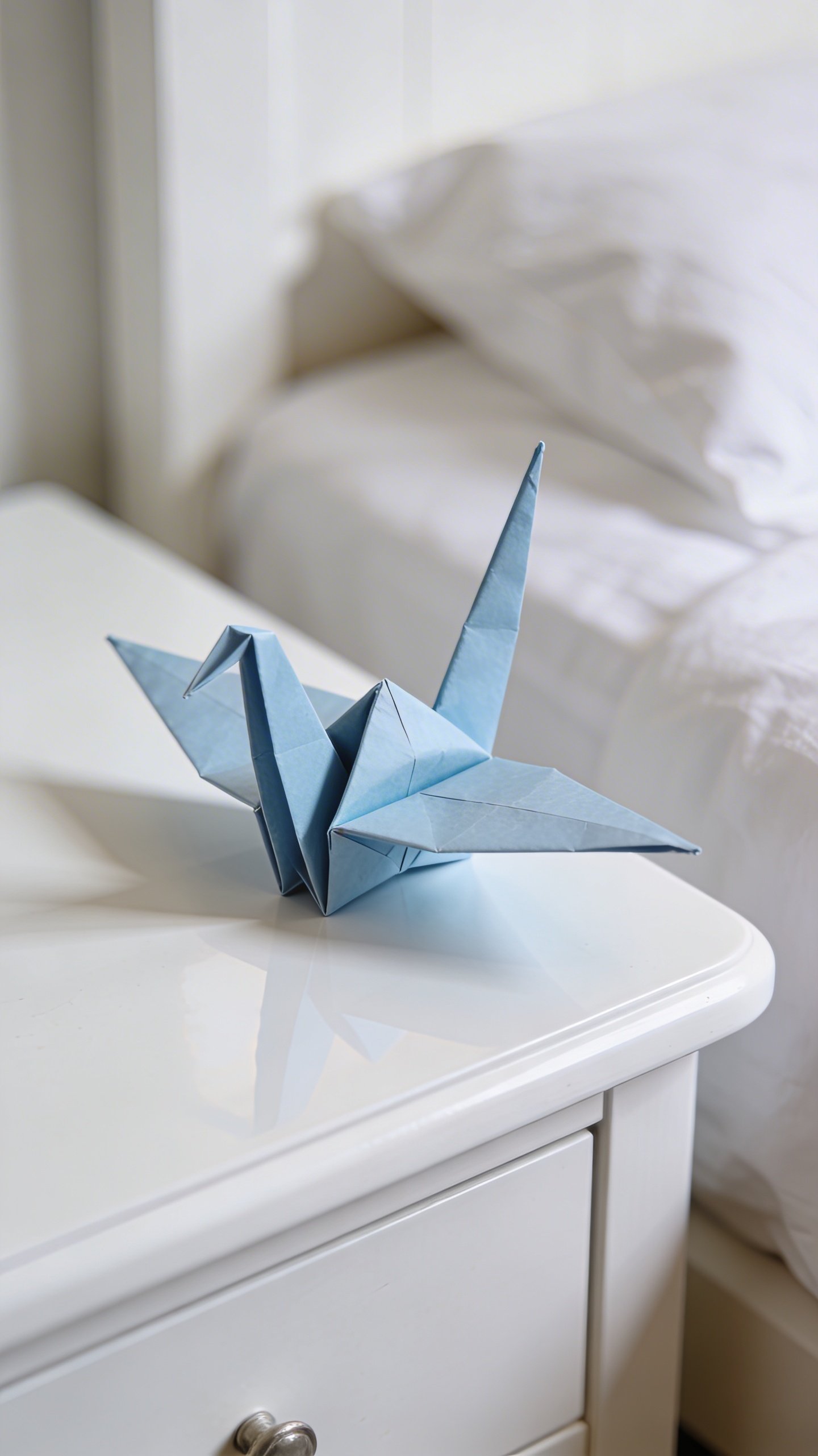 Closeup of origami paper crane on white bedside table