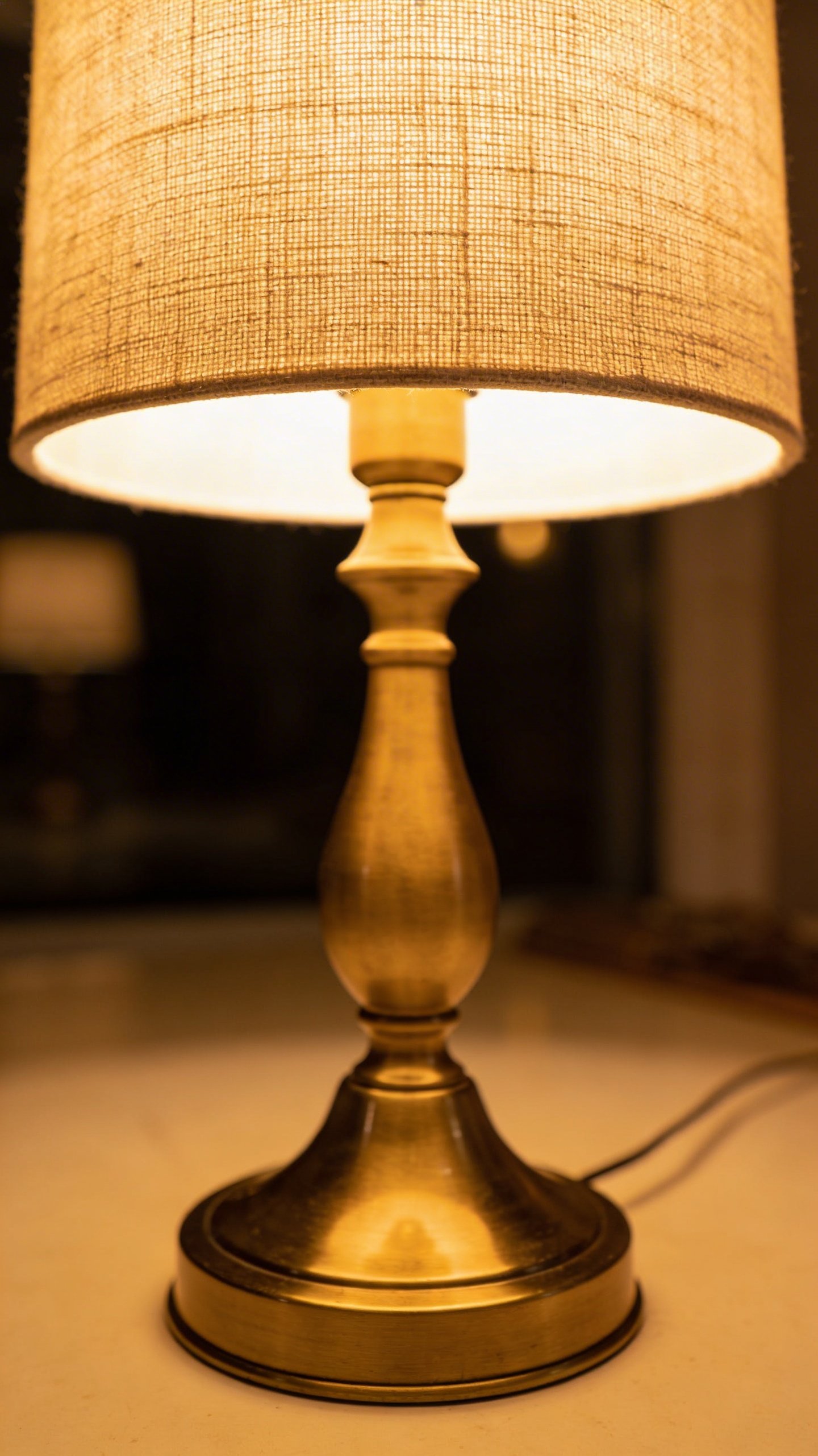 Single brass table lamp with linen shade glowing