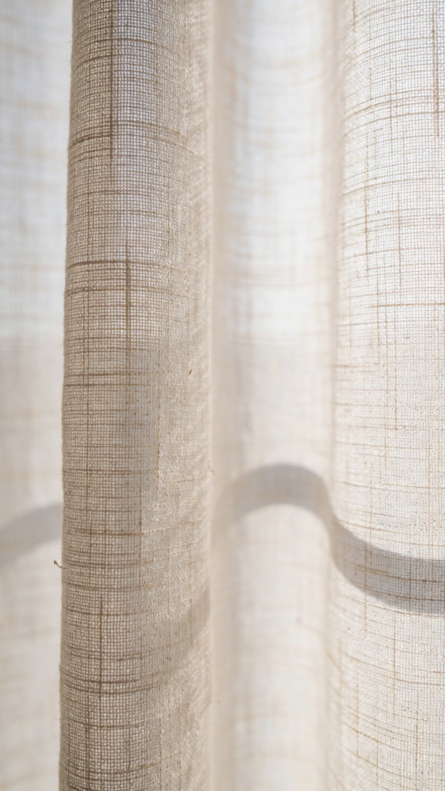 Closeup of light-colored linen curtain panel texture