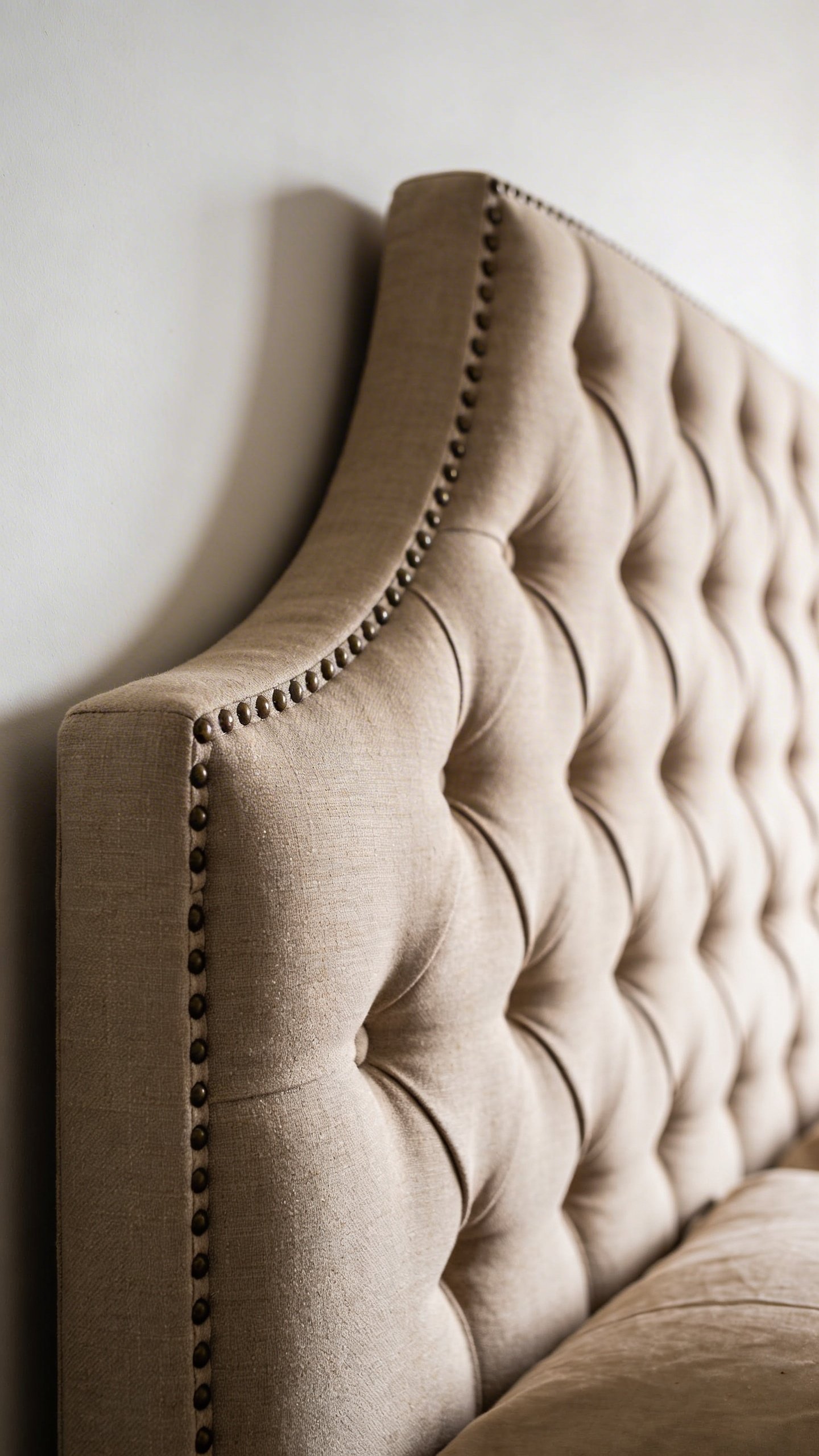 Closeup of upholstered bed headboard against white wall