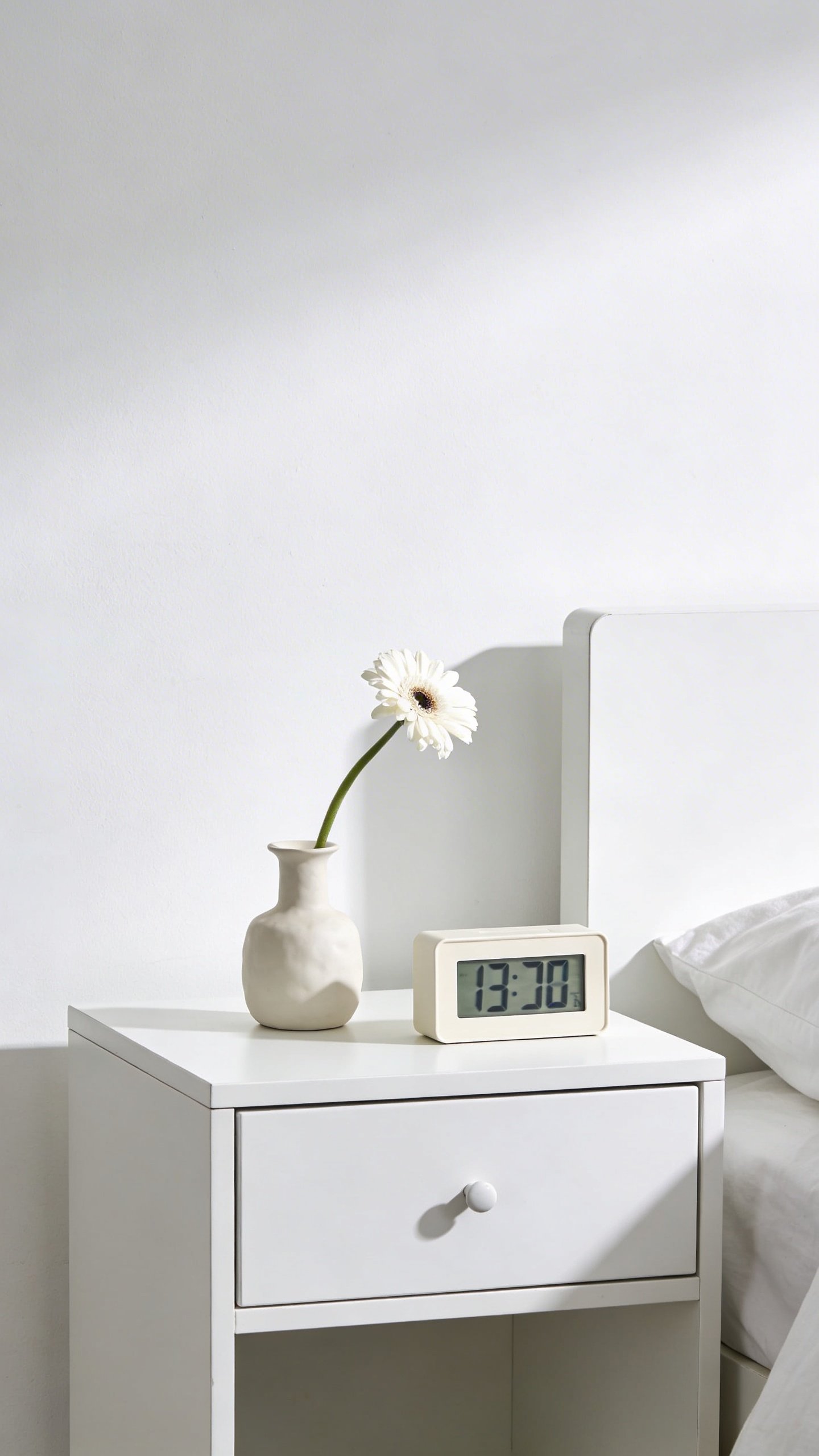 Neatly organized white bedroom nightstand with minimal decor