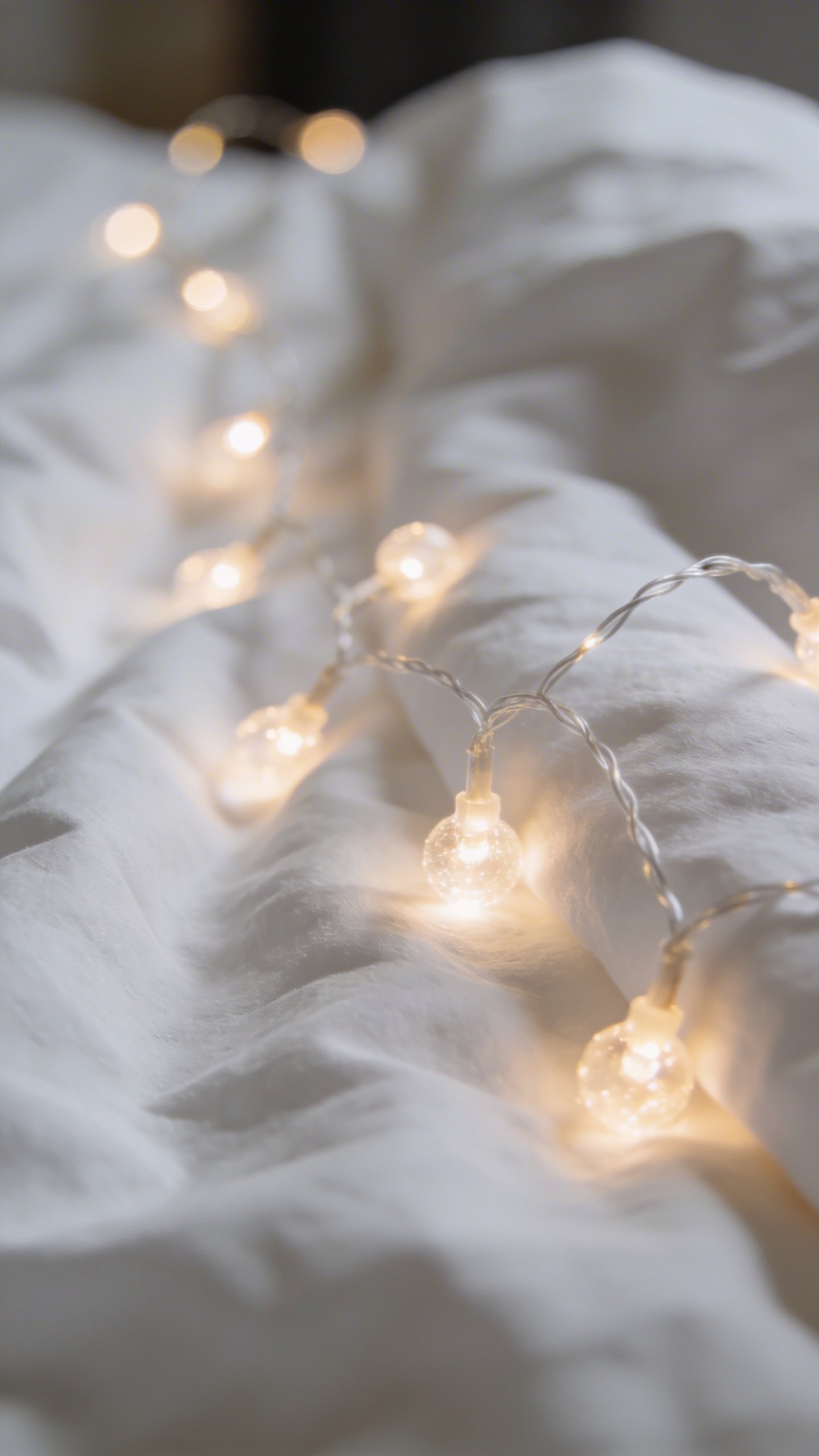Closeup of warm white fairy lights on white bedding