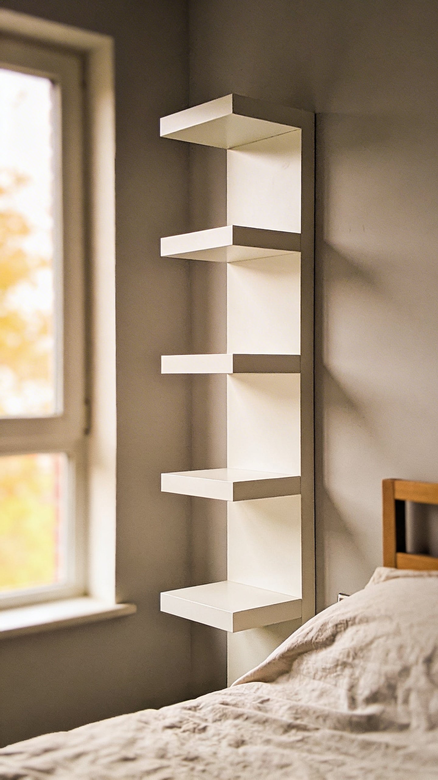 Tall white floating shelf mounted on bedroom wall
