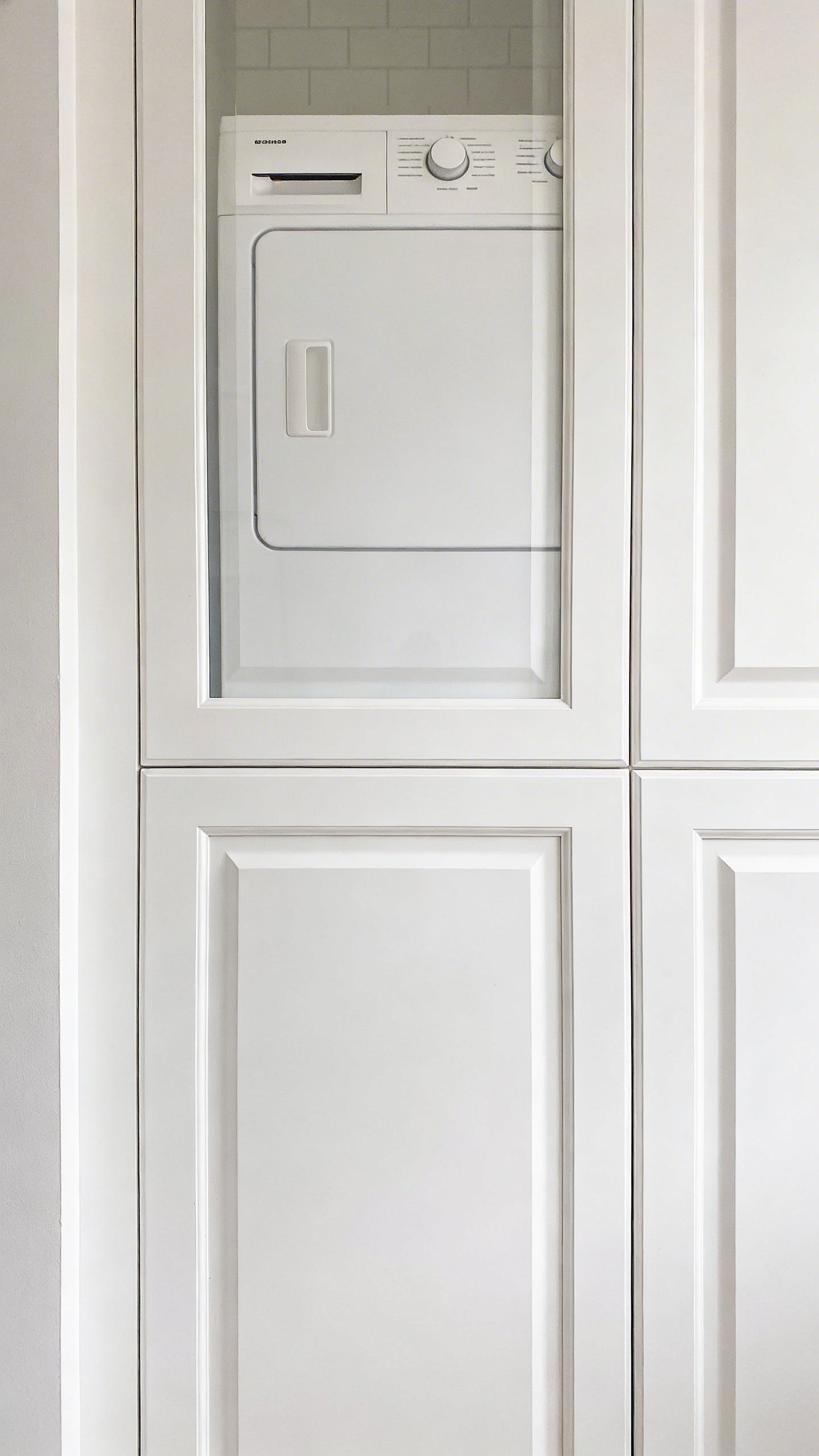 White cabinet doors concealing stackable washer dryer unit