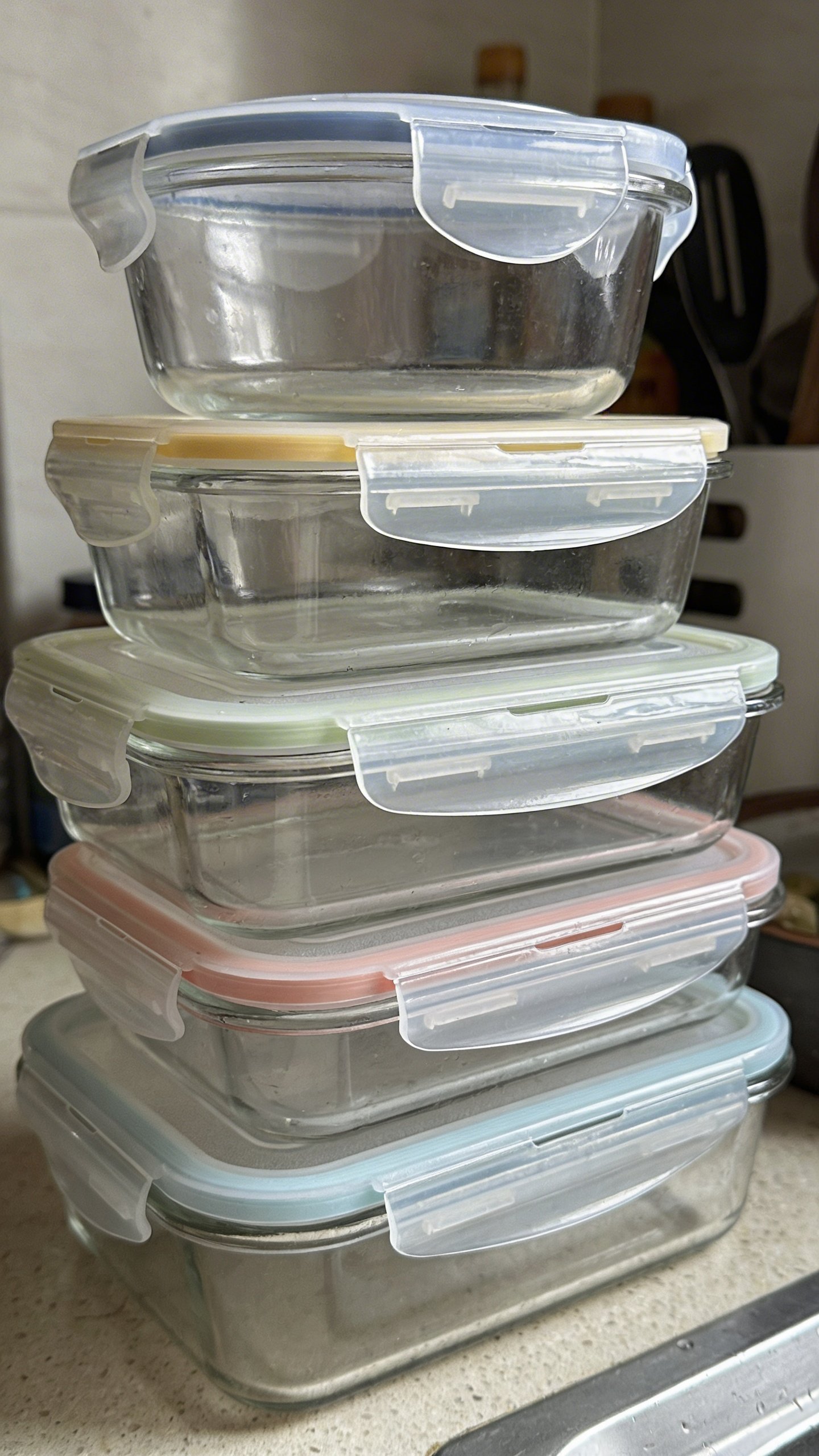 Stack of mismatched plastic container lids on counter