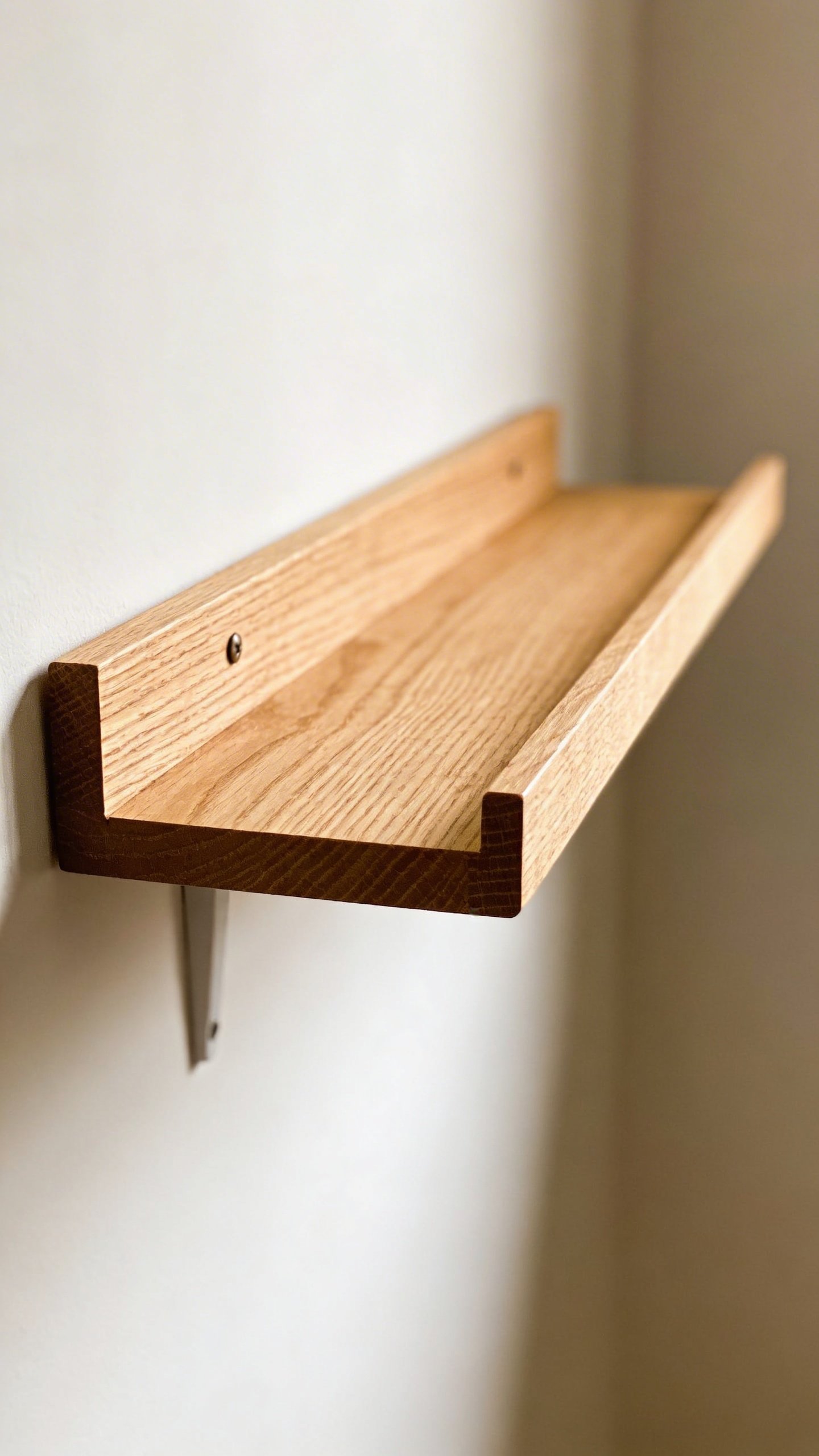Closeup of wooden floating shelf against white wall