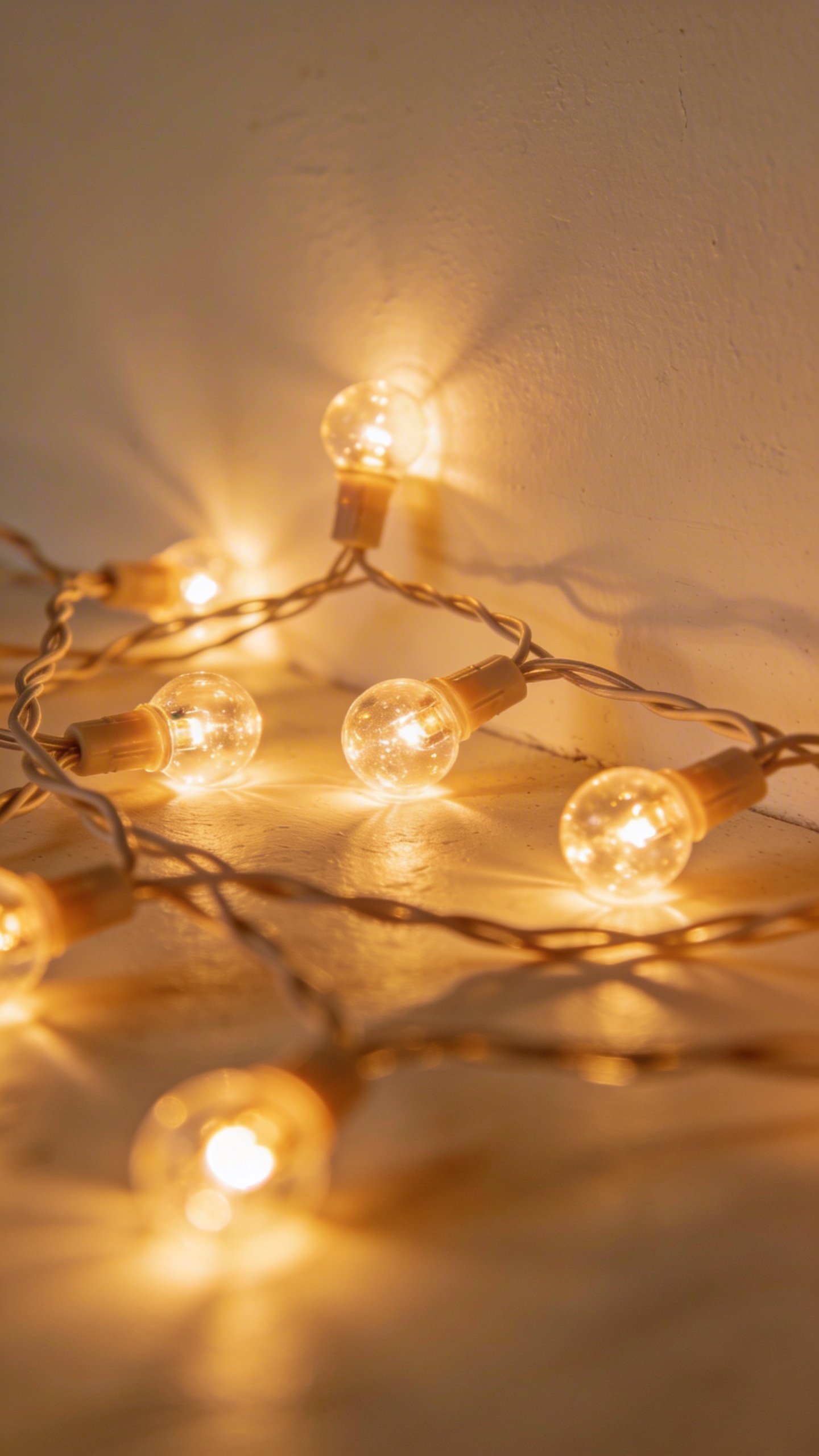 Closeup of lit string lights against white wall