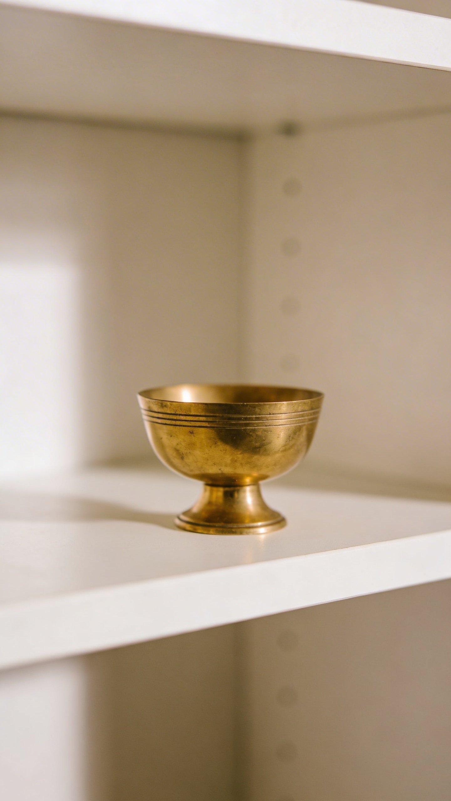Small brass decorative bowl on white shelf