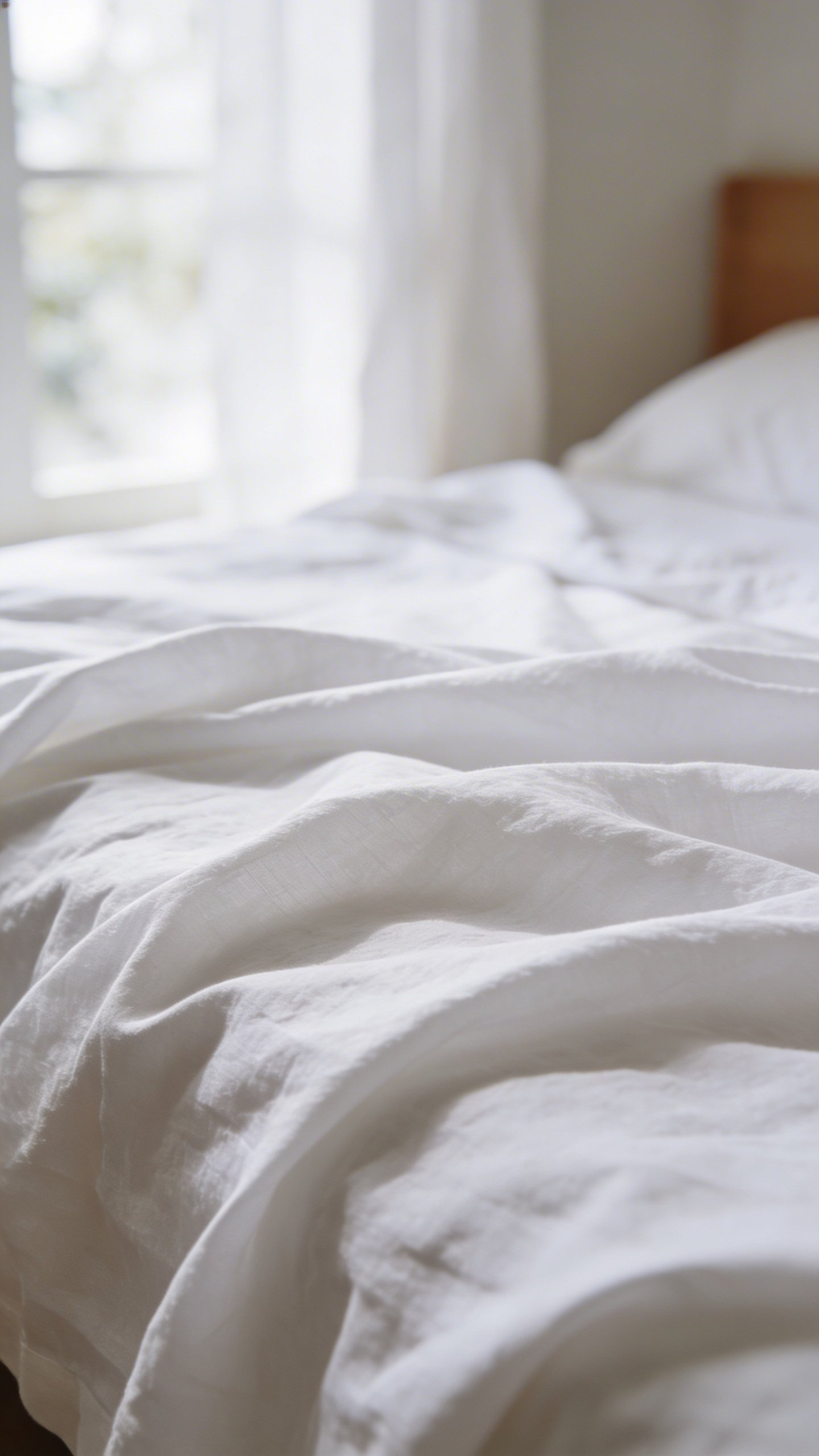 Closeup of neatly made bed with white linen sheets